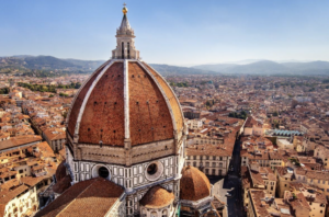 The majestic Florence Cathedral, featuring its famous dome and detailed façade is set against a picturesque Italian backdrop.